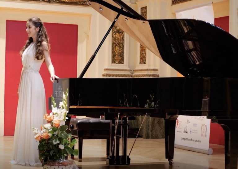 Prize winner staying on the scene of the Ehrbar Hall next to a grand piano from C. Bechstein.